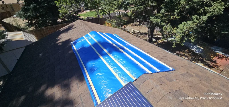 Blue tarp secured across a shingle roof during emergency protection work