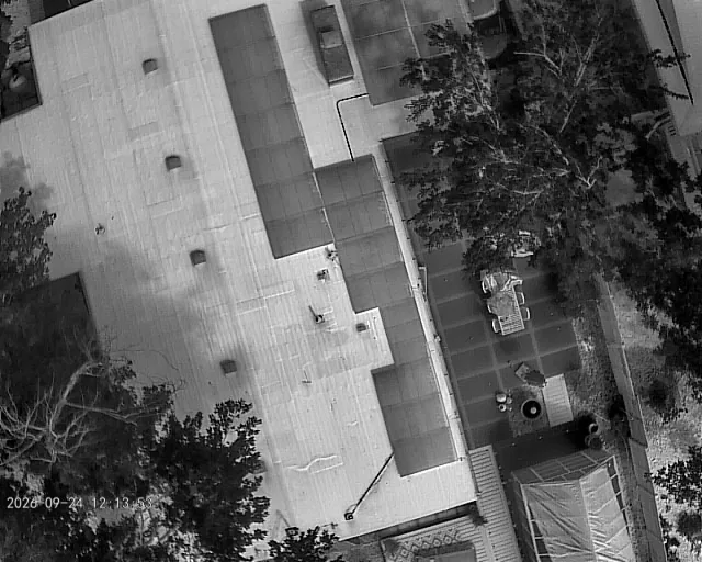 Grayscale infrared drone image of a residential roof and solar panels