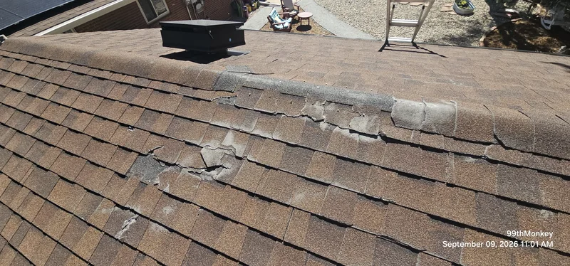 Roof inspection photograph showing damaged existing ridge-cap shingles